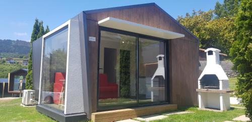 a small house with glass doors on the grass at Bungalows Portuondo parking gratuito in Mundaka