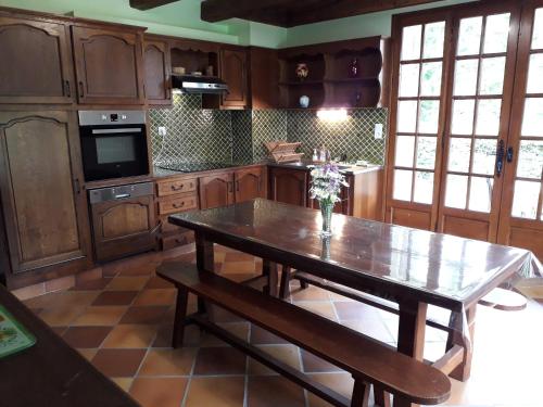 une cuisine avec une table en bois et un vase de fleurs. dans l'établissement La Maison au Cœur de l Auvergne, à Lanobre