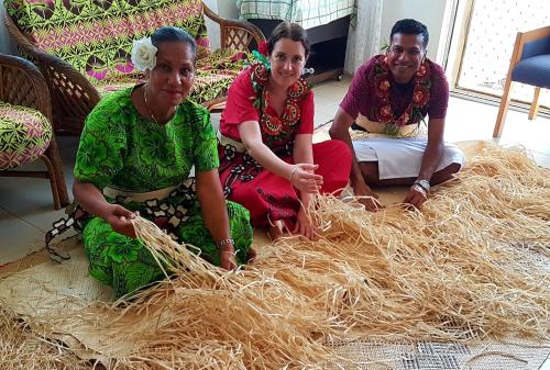 three women sitting on the floor with a pile of hay at Paea's Guest House in Nuku‘alofa