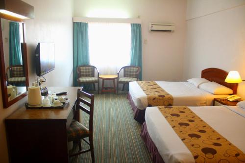 a hotel room with two beds and a table and chairs at Hotel Seri Malaysia Port Dickson in Port Dickson