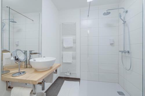 a white bathroom with a sink and a shower at Boutique Hotel Goldenes Lamm Villach in Villach