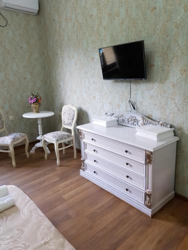a bedroom with a white dresser with a tv on the wall at Borjomi Classic Hotel in Borjomi