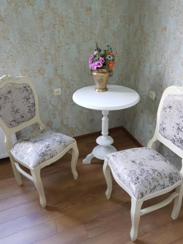 two chairs and a table with a vase of flowers at Borjomi Classic Hotel in Borjomi