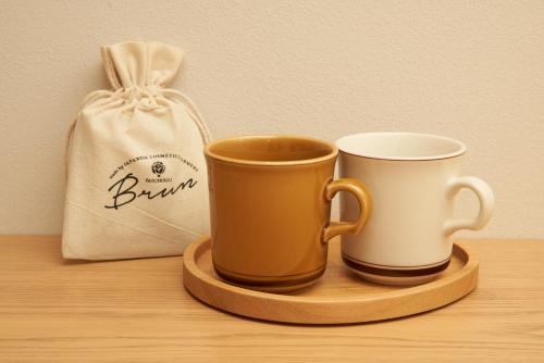 two coffee cups on a tray next to a bag at cinnamon hotel in Osaka