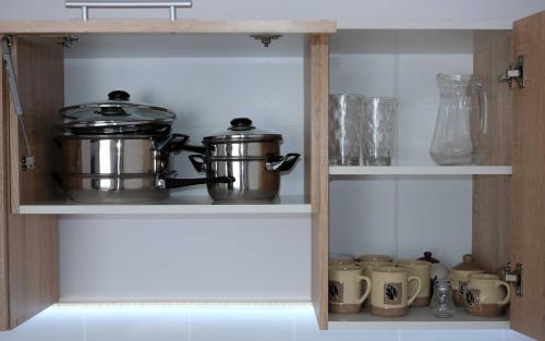 a cupboard with two pots and pans and mugs at Apartament Krystynka in Ciechocinek