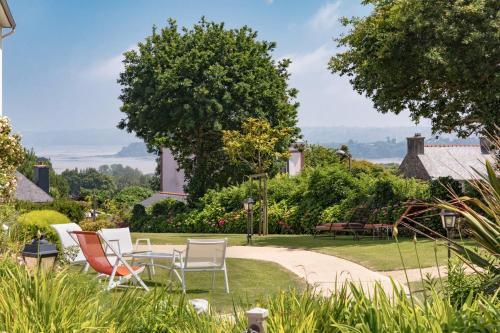 a group of chairs and tables in a garden at Hôtel Les Agapanthes in Ploubazlanec