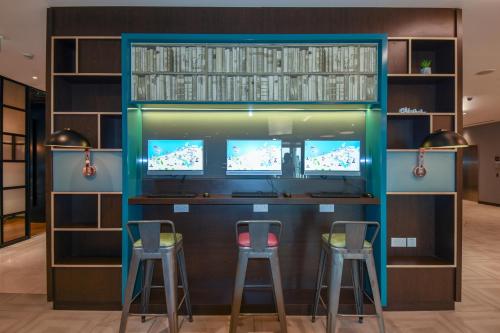 a bar with two stools and two monitors at Premier Inn Dubai International Airport in Dubai
