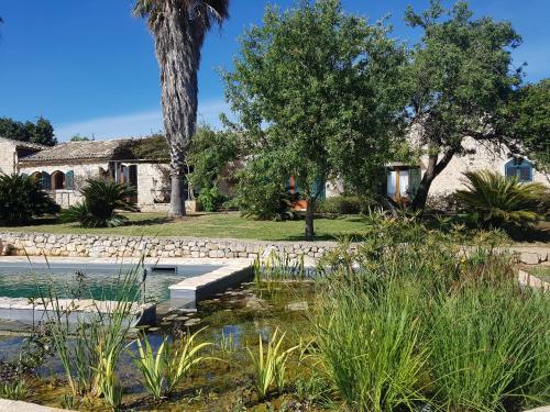 a garden with a pond in front of a house at Case Brizza in Casale Zappulla