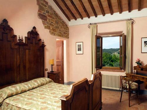 a bedroom with a bed and a desk and a window at Villa Gaeta in Montefollonico