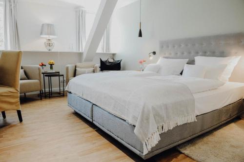 a bedroom with a large white bed and a chair at Romantik Hotel Köllners Landhaus in Celle