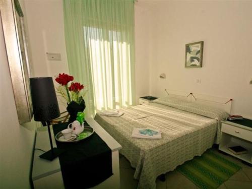 a bedroom with a bed and a vase of flowers on a table at Hotel Napoleon in San Mauro a Mare