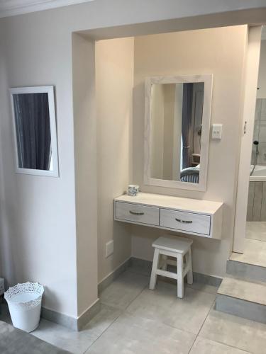 a bathroom with a vanity with a mirror and a stool at Seaside Place in Struisbaai