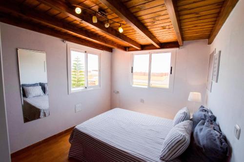 a bedroom with a bed and two windows at Casa Verde in Caleta De Fuste