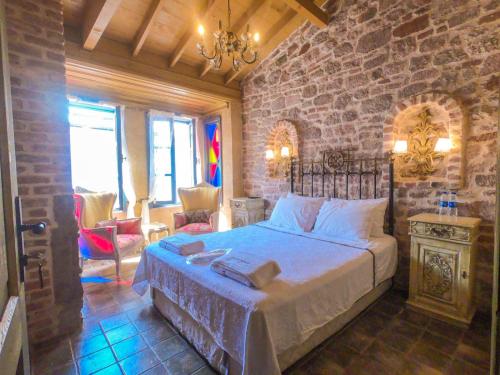 a bedroom with a bed and a stone wall at Ziyabey Konagi in Ayvalık