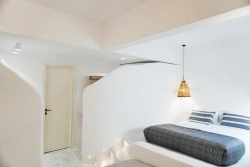 a bedroom with white walls and a bed with blue pillows at Galini Hotel in Naxos Chora