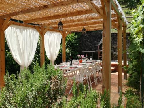 a wooden pergola with white tables and chairs under it at Chianti Best House in Greve in Chianti