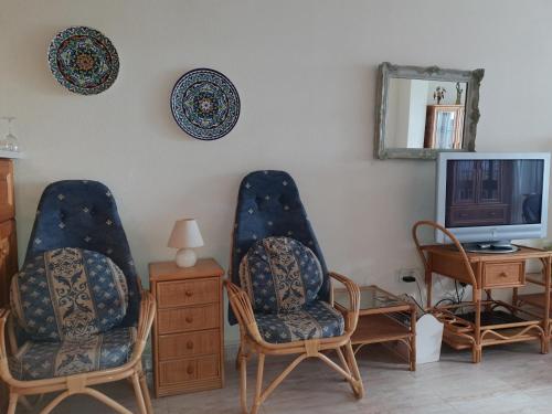 a living room with two chairs and a television at Beachfront Bungalow in Torrox Costa