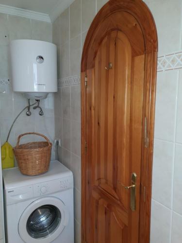 een badkamer met een wasmachine en een houten deur bij Beachfront Bungalow in Torrox Costa