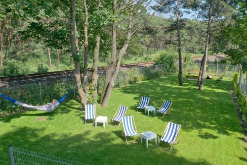 a person sleeping in a hammock in a yard with chairs at Hotel 77 Restauracja Spa in Chałupy