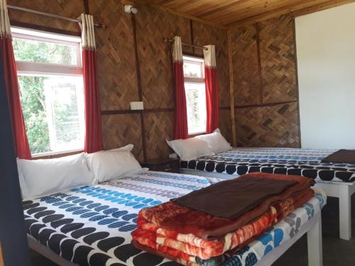 two beds in a room with two windows at Vamoose Hornbill in Mangpu