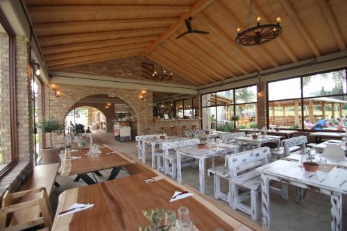 um restaurante com mesas e cadeiras brancas e janelas em Honigtal Farmland em Agios Georgios Pagon