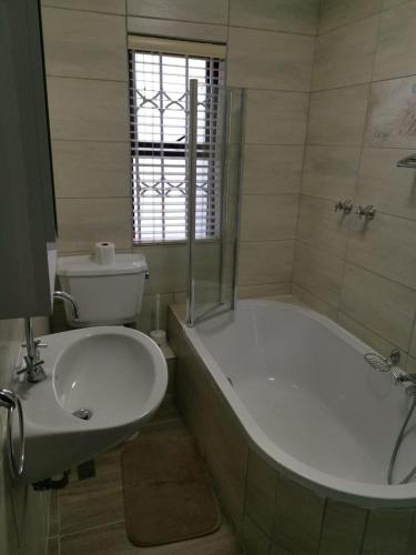 a bathroom with a tub and a toilet and a sink at Serengeti Self Catering Units in Bellville