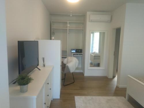 ein weißes Wohnzimmer mit einem TV und einem Schreibtisch in der Unterkunft App Neno in Murine