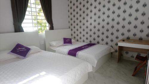 two beds in a room with a desk and a window at Lavender Tan Thanh Hotel mini resort in Cong Thanh (3)