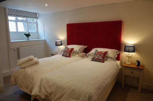 a bedroom with a large bed with a red headboard at The Yard House in Sherborne