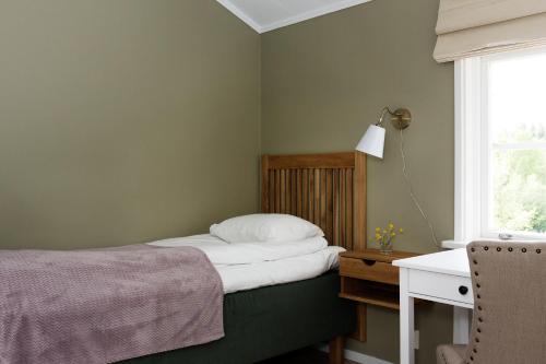 a bedroom with a bed and a desk and a window at Hotel Kallgården in Järpen