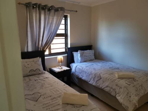 a bedroom with two beds next to a window at Serengeti Self Catering Units in Bellville