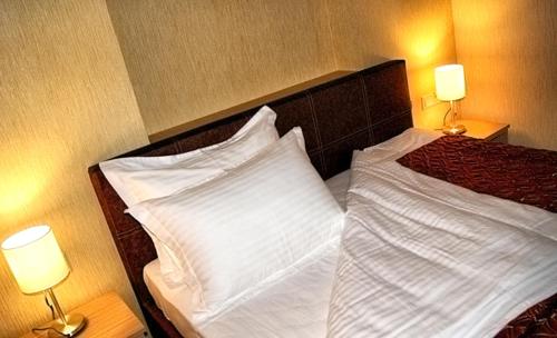 a bedroom with a bed with white sheets and two lamps at Апарт готель Aqua Paradise Совіньйон in Odesa