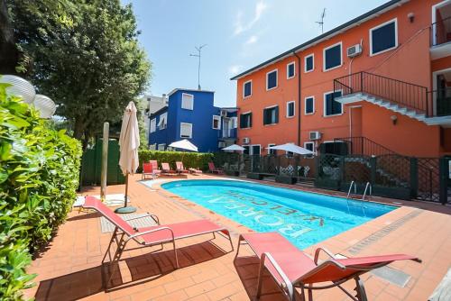 uma piscina com cadeiras e um edifício em Villa Veneta em Bibione