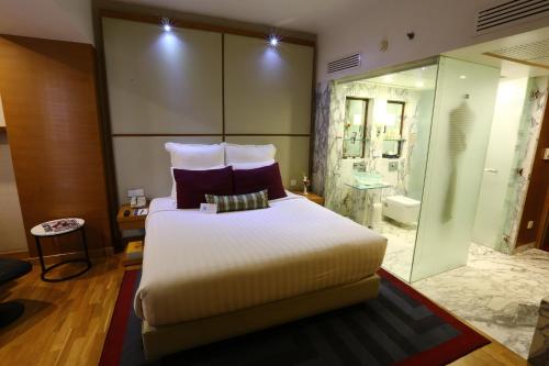 a bedroom with a large bed and a bathroom at Avari Towers Karachi in Karachi