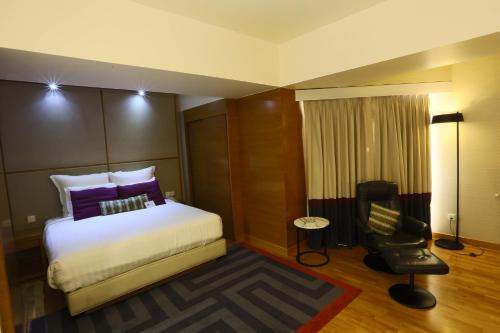 a hotel room with a bed and a chair at Avari Towers Karachi in Karachi