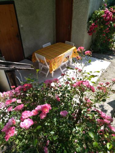a table and chairs in a garden with pink flowers at Bel appartement au rez de chaussée d'un chalet in Jarrier