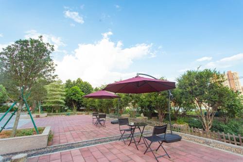 廈門市にあるXiamen Guiran Hostelのテーブルと椅子と傘のあるパティオ