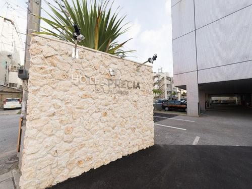 a stone wall with a hotel sign on the side of a street at Okinawa Hotel Precia in Naha