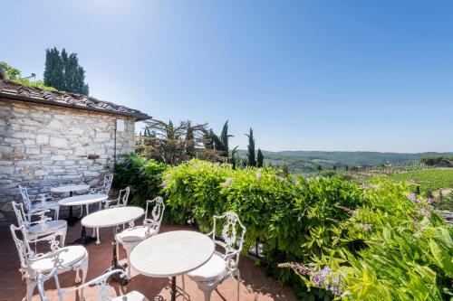 a patio with tables and chairs and a stone building at Relais Vignale & Spa in Radda in Chianti