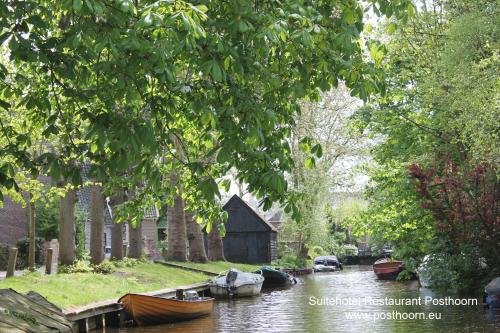 a group of boats on a river with a house at Suitehotel Posthoorn in Monnickendam