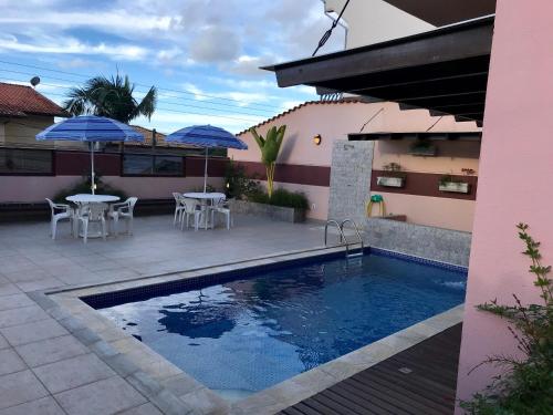 a swimming pool with tables and umbrellas next to a house at Casa Bela Vista in Guararema