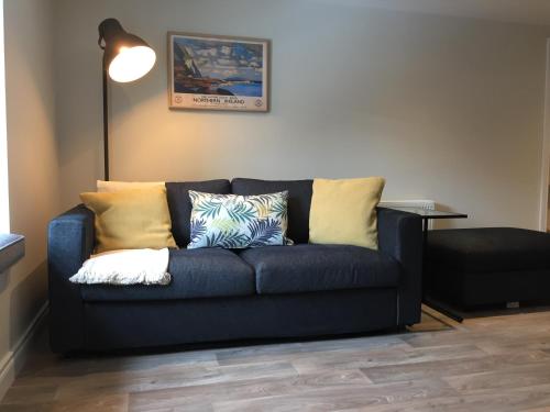 a blue couch with pillows on it in a living room at Bush House Accommodation - The Courthouse Apartment in Bushmills