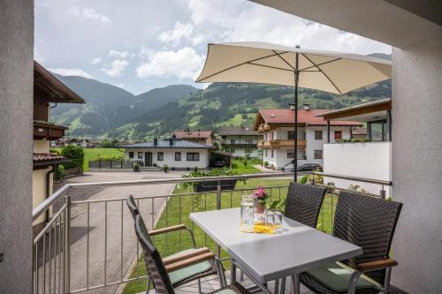 a white table with an umbrella on a balcony at Ferienwohnung Taschler in Ramsau im Zillertal