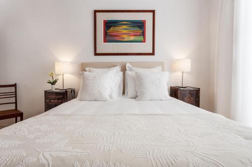 1 dormitorio con 1 cama blanca y 2 lámparas en Casa das Arcadas, com free garagem - Praça de Giraldo, en Évora