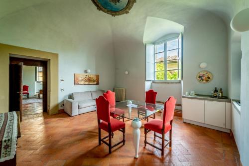 sala de estar con mesa de cristal y sillas rojas en Historical Renaissance Palace, en Montepulciano