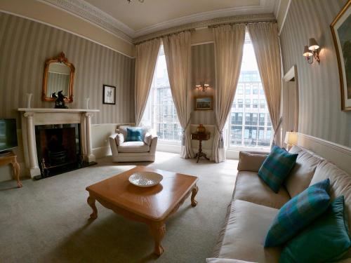 a living room with a couch and a fireplace at Escape To Edinburgh @ Albyn Place in Edinburgh