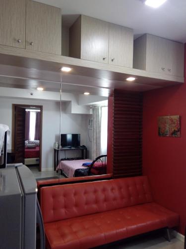 a living room with a red couch and a bedroom at Nica's Place Property Management Services at Horizons 101 Condominium in Cebu City