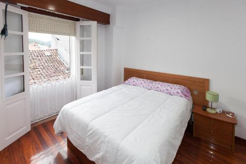 sypialnia z białym łóżkiem i oknem w obiekcie Duplex Familiar w mieście Ribadavia