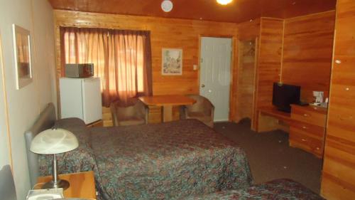Habitación de hotel con cama, escritorio y mesa. en Dreamland Motel, en Moose Jaw