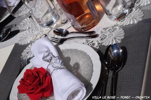 una mesa con un plato con una rosa roja. en Luxury VILLA LE ROSE, en Poreč